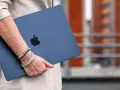 Donna con un MacBook blu, logo Apple visibile. La pulizia del mac è evidente, pronto per nuove avventure.