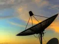 Antenna parabolica in controluce al tramonto, pronta a connettersi al mondo tramite internet satellitare.