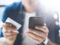 Persona che usa uno smartphone e una carta di credito per configurare un piano cellulare.