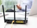 Router con antenne per connessione wifi senza linea fissa. In background, una persona usa uno smartphone.