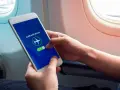 Mani che attivano la modalità aereo sul telefono, seduti vicino al finestrino di un aereo.