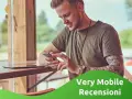 Uomo con tatuaggi guarda il suo smartphone, leggendo le very opinioni su "Very Mobile Recensioni".