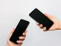 Due mani tengono due smartphone neri, uno in primo piano e uno più lontano, illustrando come trasferire i dati da un telefono all'altro.