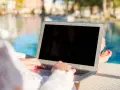 Donna lavora al laptop vicino alla piscina, godendosi l'internet temporaneo per la seconda casa.