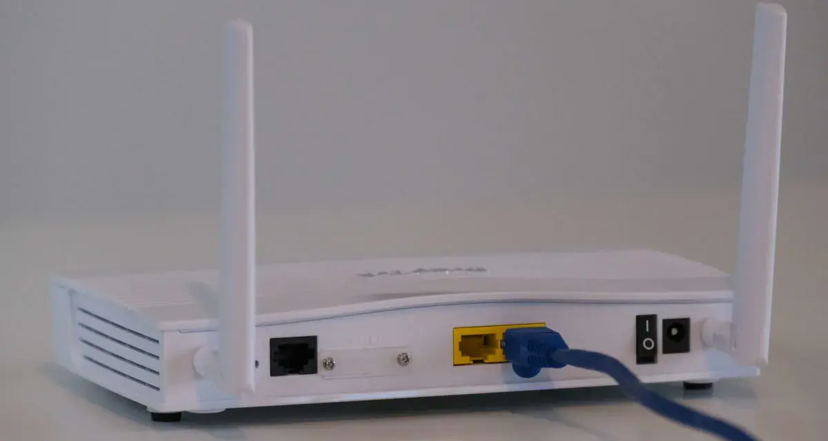 Router bianco con antenne, cavo blu collegato. Soluzione per internet a casa senza fibra.