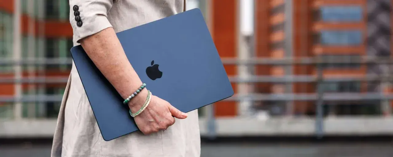 Donna con un MacBook blu, logo Apple visibile. La pulizia del mac è evidente, pronto per nuove avventure.