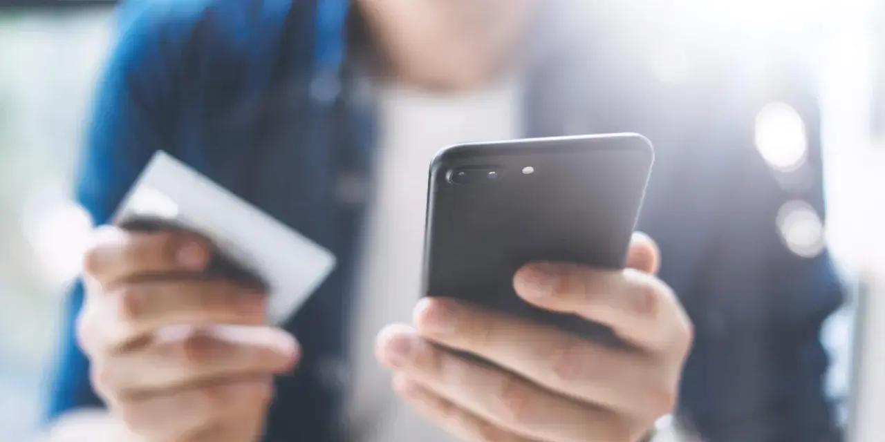 Persona che usa uno smartphone e una carta di credito per configurare un piano cellulare.