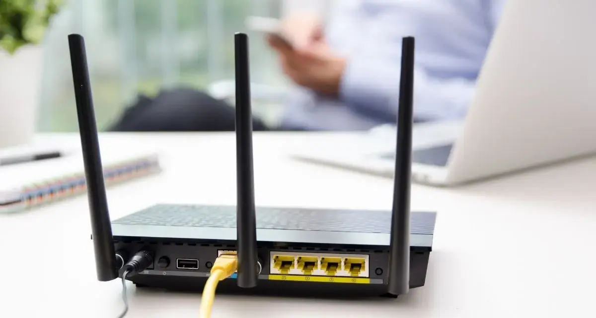 Router con antenne per connessione wifi senza linea fissa. In background, una persona usa uno smartphone.