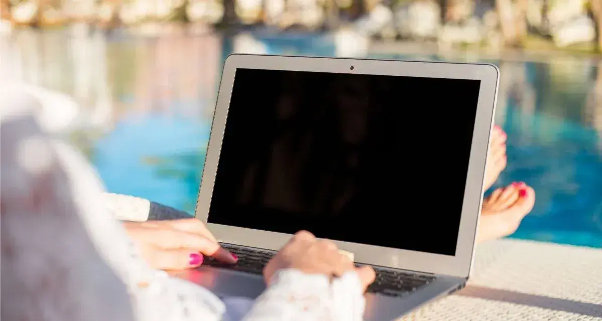 Donna lavora al laptop vicino alla piscina, godendosi l'internet temporaneo per la seconda casa.
