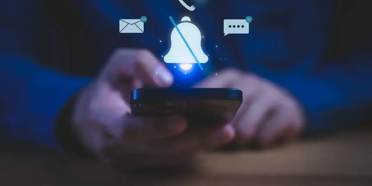 Mani che tengono uno smartphone, con icone di notifiche (email, messaggi, chiamate) e una campana barrata, per illustrare come silenziare le notifiche.