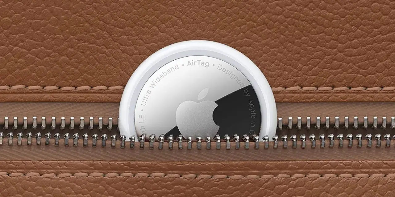 Un AirTag Apple sporge da una cerniera di una borsa in pelle marrone. Scopri airtag come funziona per ritrovare i tuoi oggetti.