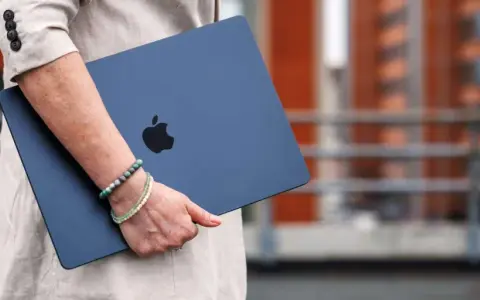 Donna con un MacBook blu, logo Apple visibile. La pulizia del mac è evidente, pronto per nuove avventure.