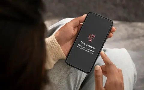 Mani che tengono uno smartphone con un messaggio di avviso "Temperatura". È ora di capire come raffreddare il telefono.