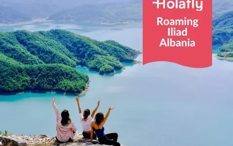 Tre amiche ammirano un lago turchese in Albania, con la scritta "Holafly Roaming Iliad Albania".