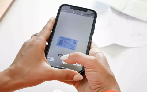 Mani che usano uno smartphone per scannerizzare un documento d'identità. L'app mostra un'anteprima del documento.