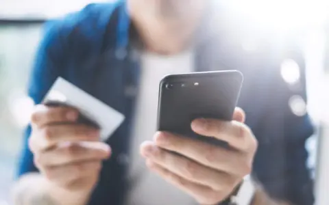 Persona che usa uno smartphone e una carta di credito per configurare un piano cellulare.