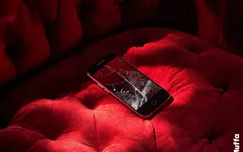 Telefono con schermo rotto su un divano rosso. Non riesco a spegnere il telefono, è bloccato.