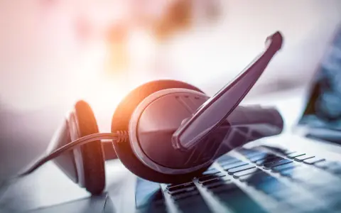 Cuffie con microfono su tastiera. Per sapere come parlare con un operatore Fastweb non cliente, cerca online o contatta i canali dedicati.