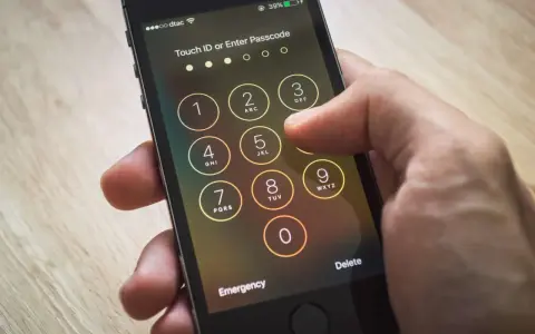 Dito si vede come sbloccare iPhone inserendo il codice. La mano preme i tasti numerici sullo schermo.