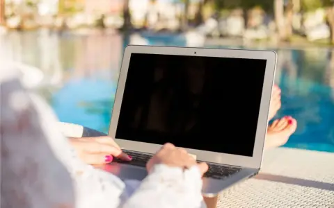 Donna lavora al laptop vicino alla piscina, godendosi l'internet temporaneo per la seconda casa.