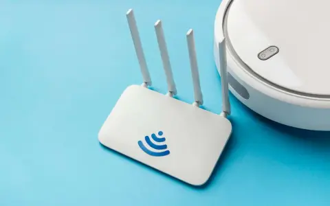 Un router Wi-Fi bianco con logo blu e un robot aspirapolvere bianco su sfondo azzurro. Cos'è un router? È il cuore della tua connessione internet.