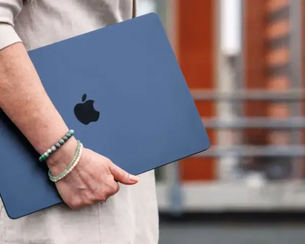 Donna con un MacBook blu, logo Apple visibile. La pulizia del mac è evidente, pronto per nuove avventure.