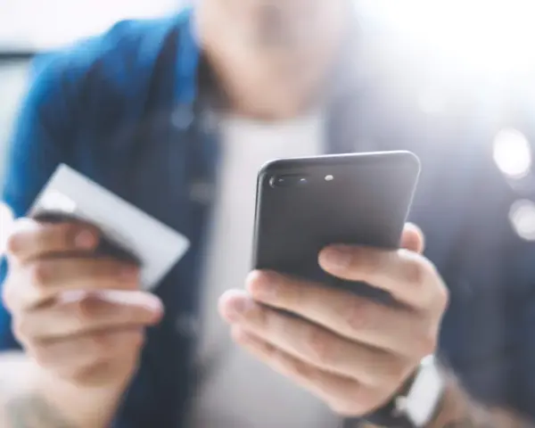Persona che usa uno smartphone e una carta di credito per configurare un piano cellulare.