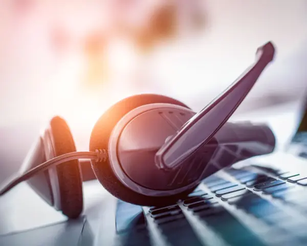 Cuffie con microfono su tastiera. Per sapere come parlare con un operatore Fastweb non cliente, cerca online o contatta i canali dedicati.