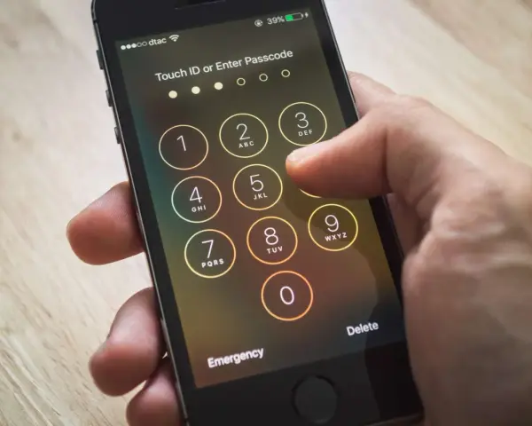 Dito si vede come sbloccare iPhone inserendo il codice. La mano preme i tasti numerici sullo schermo.