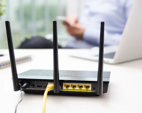 Router con antenne per connessione wifi senza linea fissa. In background, una persona usa uno smartphone.