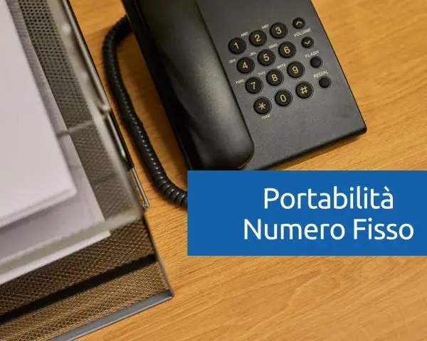 Telefono fisso e documenti su scrivania in legno. Testo: "Portabilità Numero Fisso".