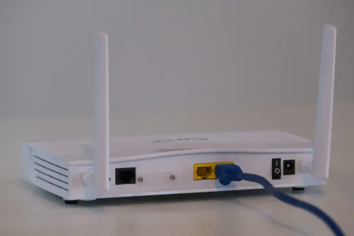 Router bianco con antenne, cavo blu collegato. Soluzione per internet a casa senza fibra.