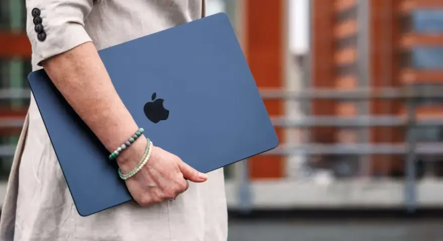 Donna con un MacBook blu, logo Apple visibile. La pulizia del mac è evidente, pronto per nuove avventure.