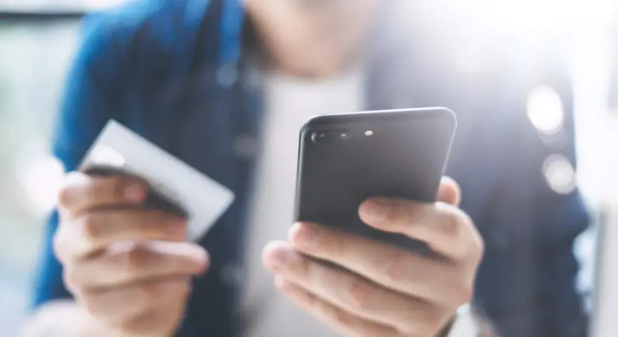 Persona che usa uno smartphone e una carta di credito per configurare un piano cellulare.