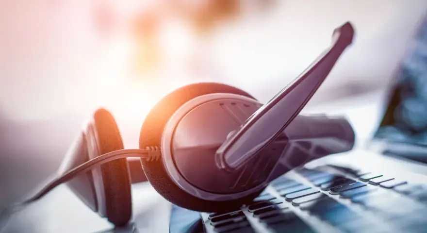 Cuffie con microfono su tastiera. Per sapere come parlare con un operatore Fastweb non cliente, cerca online o contatta i canali dedicati.