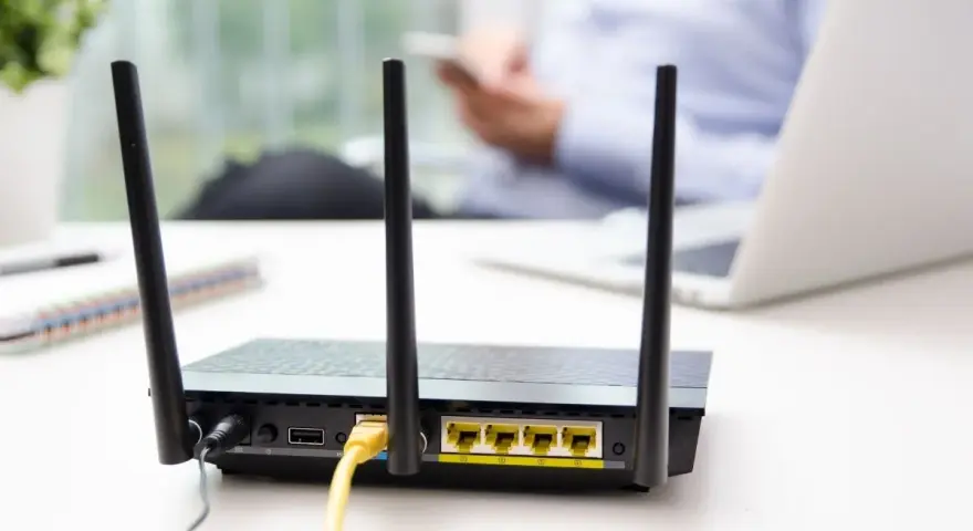 Router con antenne per connessione wifi senza linea fissa. In background, una persona usa uno smartphone.