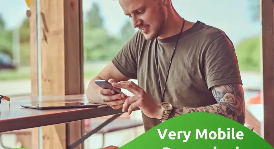Uomo con tatuaggi guarda il suo smartphone, leggendo le very opinioni su "Very Mobile Recensioni".