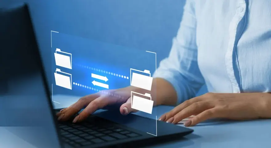 Mani su tastiera laptop, interfaccia digitale con icone di cartelle e frecce che indicano il trasferimento dati, utile per capire come inviare video pesanti.