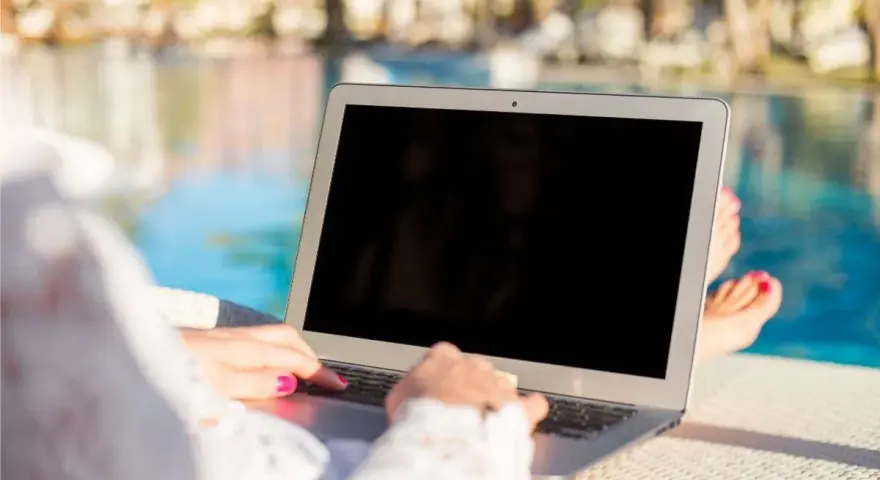 Donna lavora al laptop vicino alla piscina, godendosi l'internet temporaneo per la seconda casa.