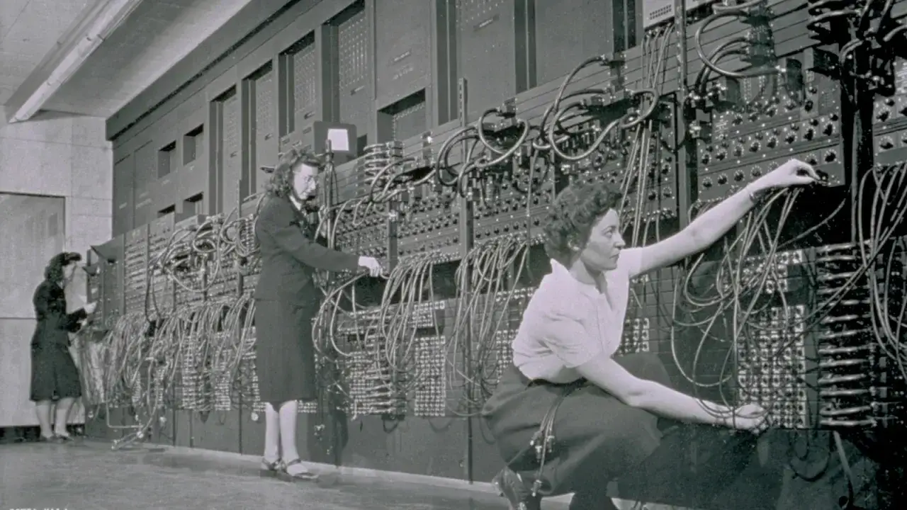 Donne lavorano su un enorme pannello di cavi e interruttori, il primo computer.